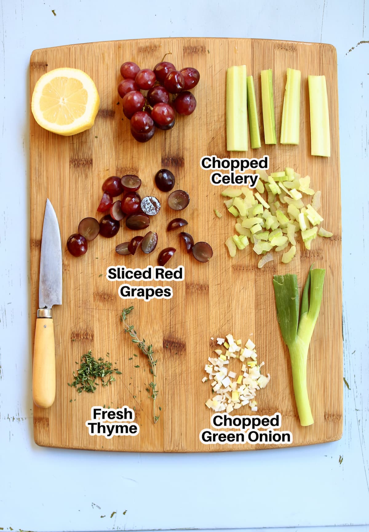 a cutting board with celery, grapes, onion, lemon and thyme for chicken salad