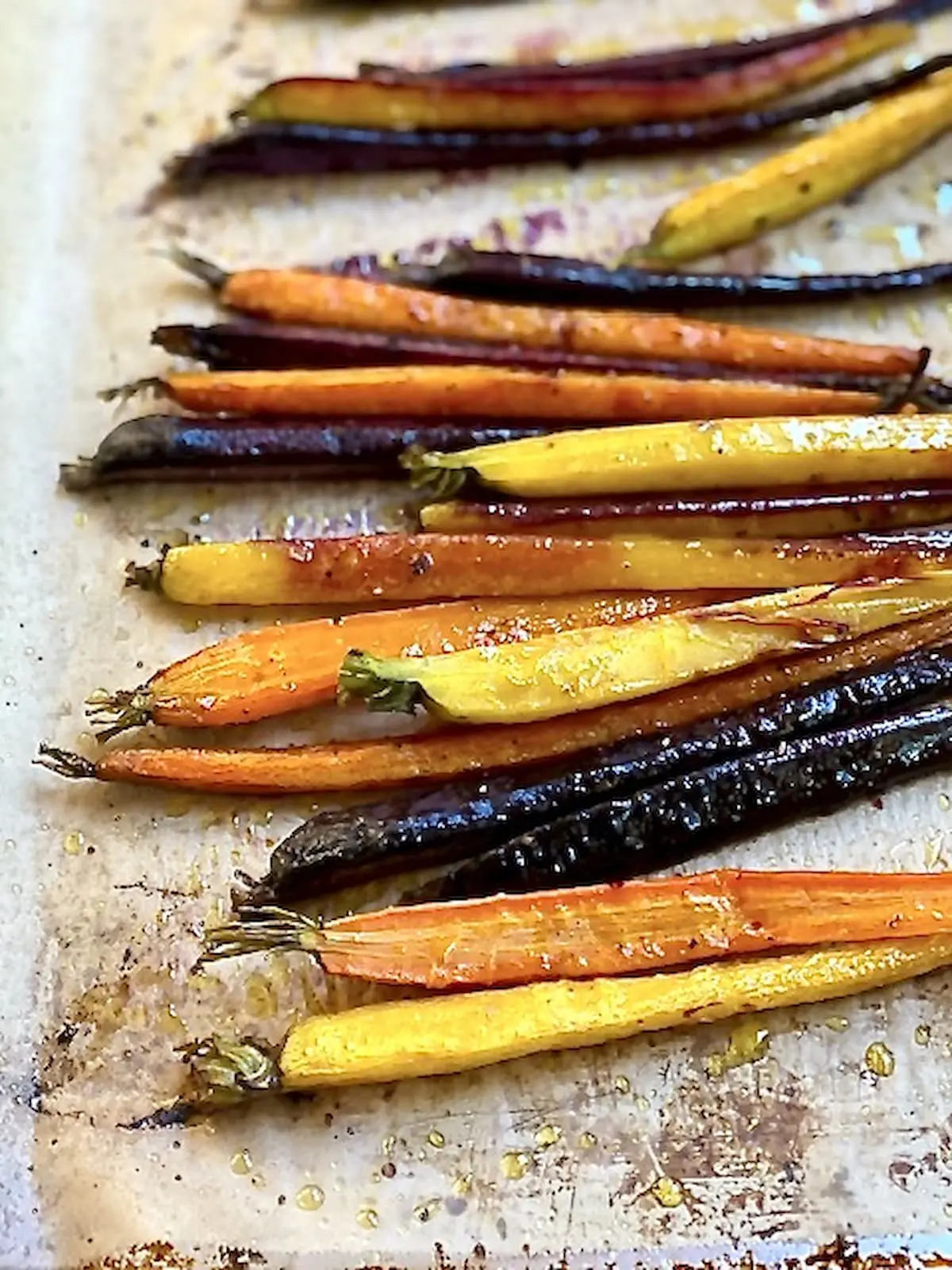 roasted carrots of different colors right out of the oven on a baking sheet.