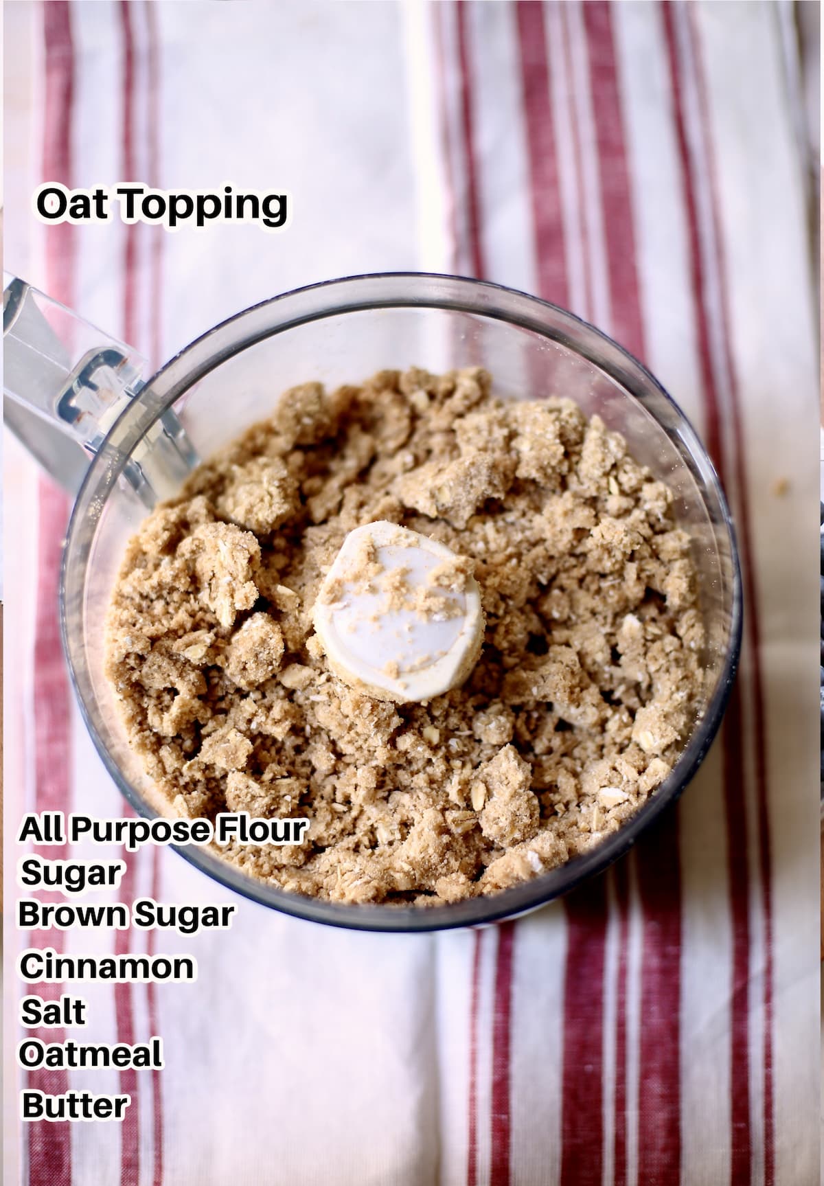 a food processor sits on a striped cloth with text overlay on top saying the ingredients of this oat topping.