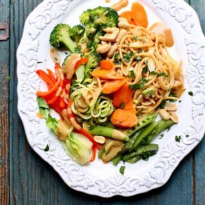 a white dish with noodles and vegetables on it.