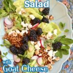 a salad on a long blue plate with text overlay of the recipe name, blackberry salad with goat cheese