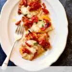 a white platter with baked pasta and a fork alongside.