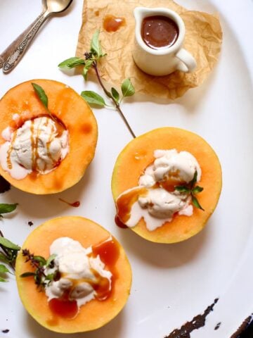 a white tray of cantaloupe and ice cream and caramel sauce.