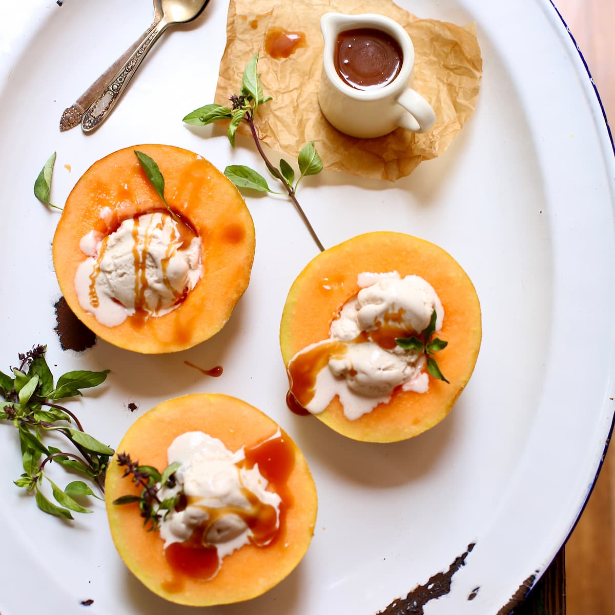 a white tray of cantaloupe and ice cream and caramel sauce.