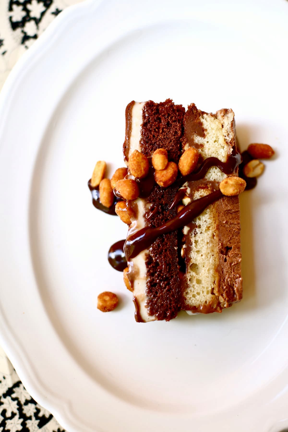 a piece of ice cream cake with nuts on top on a white platter.