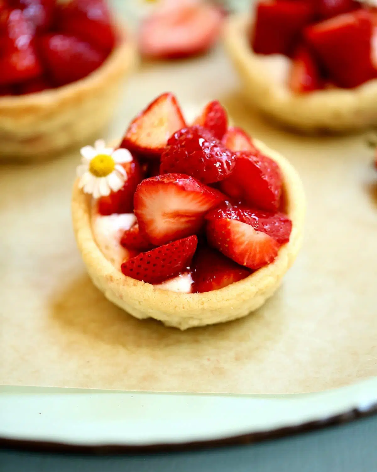 a mini strawberry pie in a cookie cup with whipped cream sitting on a serving tray.