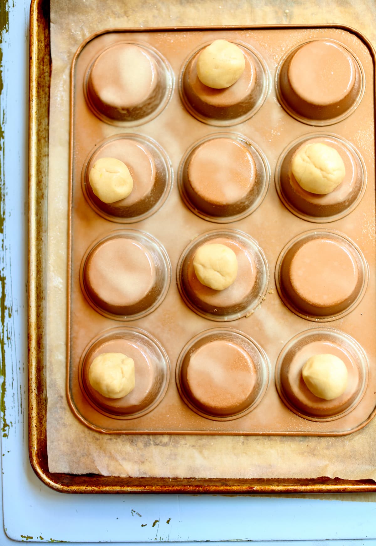 a copper colored muffin tin upsidedown with cookie dough balls on top