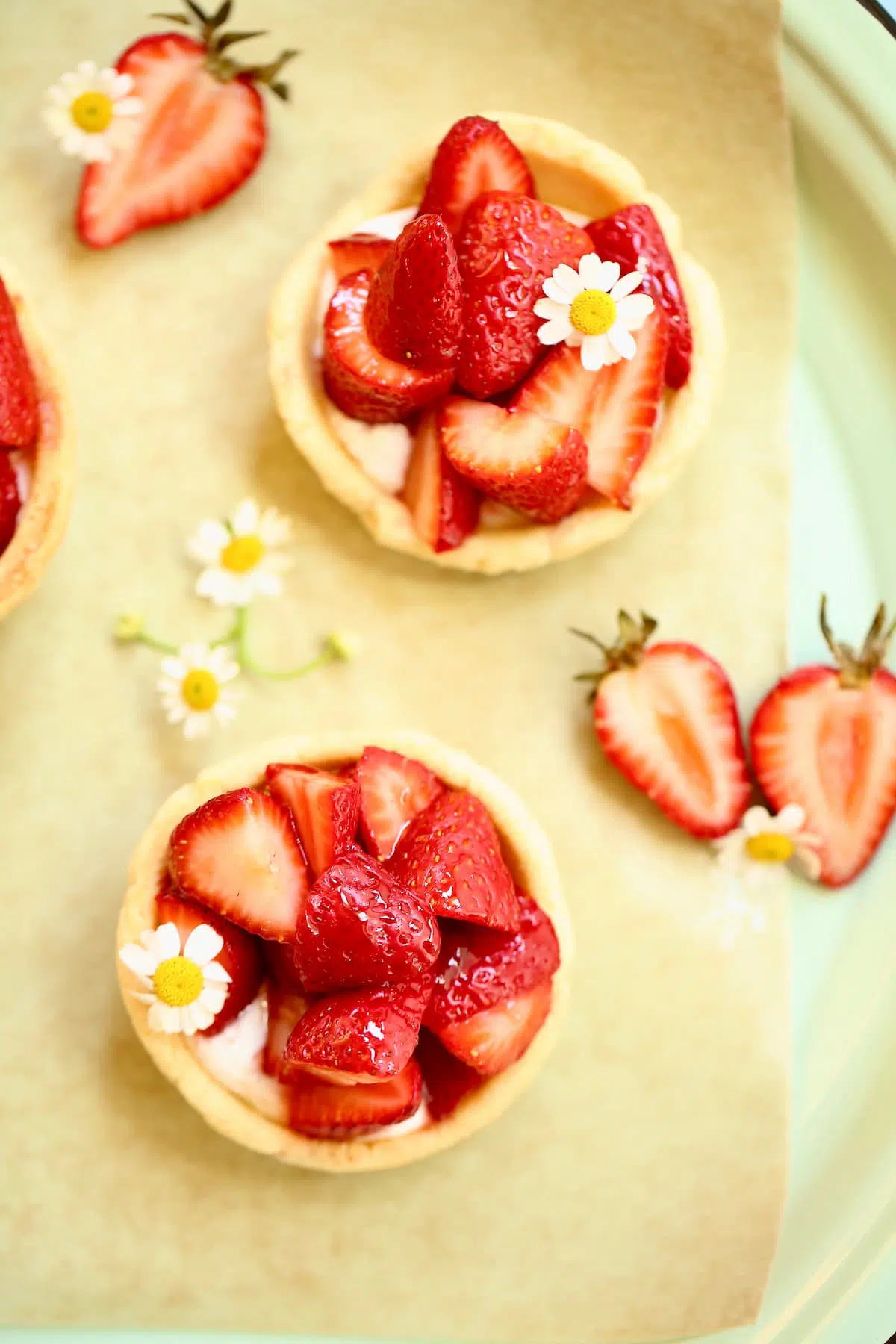three small strawberry pies with small flowers on a serving tray.