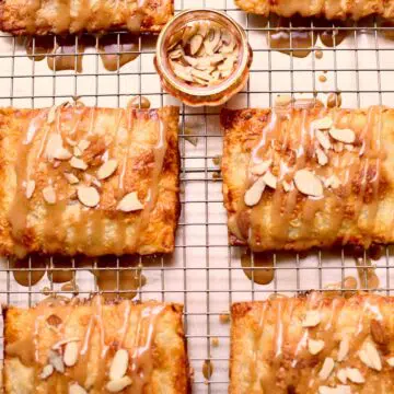 a wire rack of hand pies with a small cup of sliced almonds in the middle. s