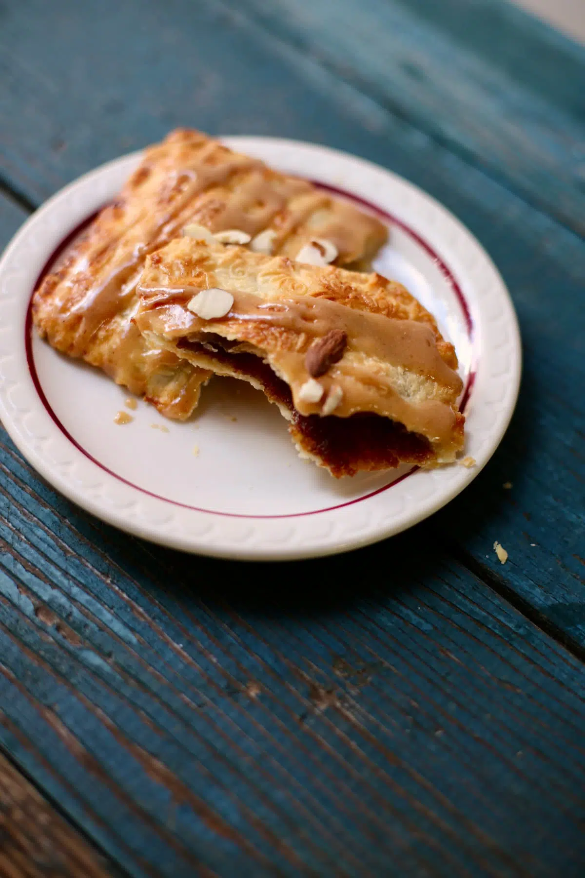 an apple butter hand pie on a small white plate, torn in half, showing the insides. The plate is on a blue table.