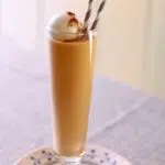 a tall thin glass of pumpkin spice milkshake with a text overlay saying the recipe name.