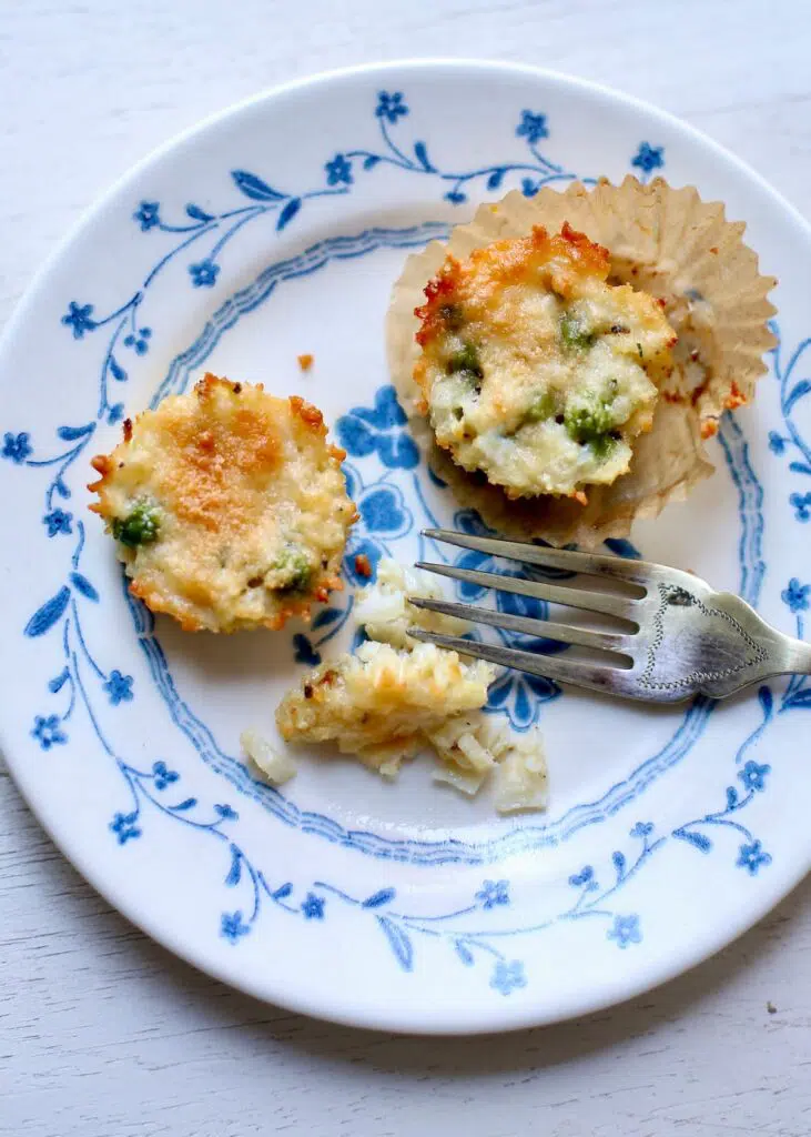 a blue and white plate with two cauliflower appetizers and a fork.