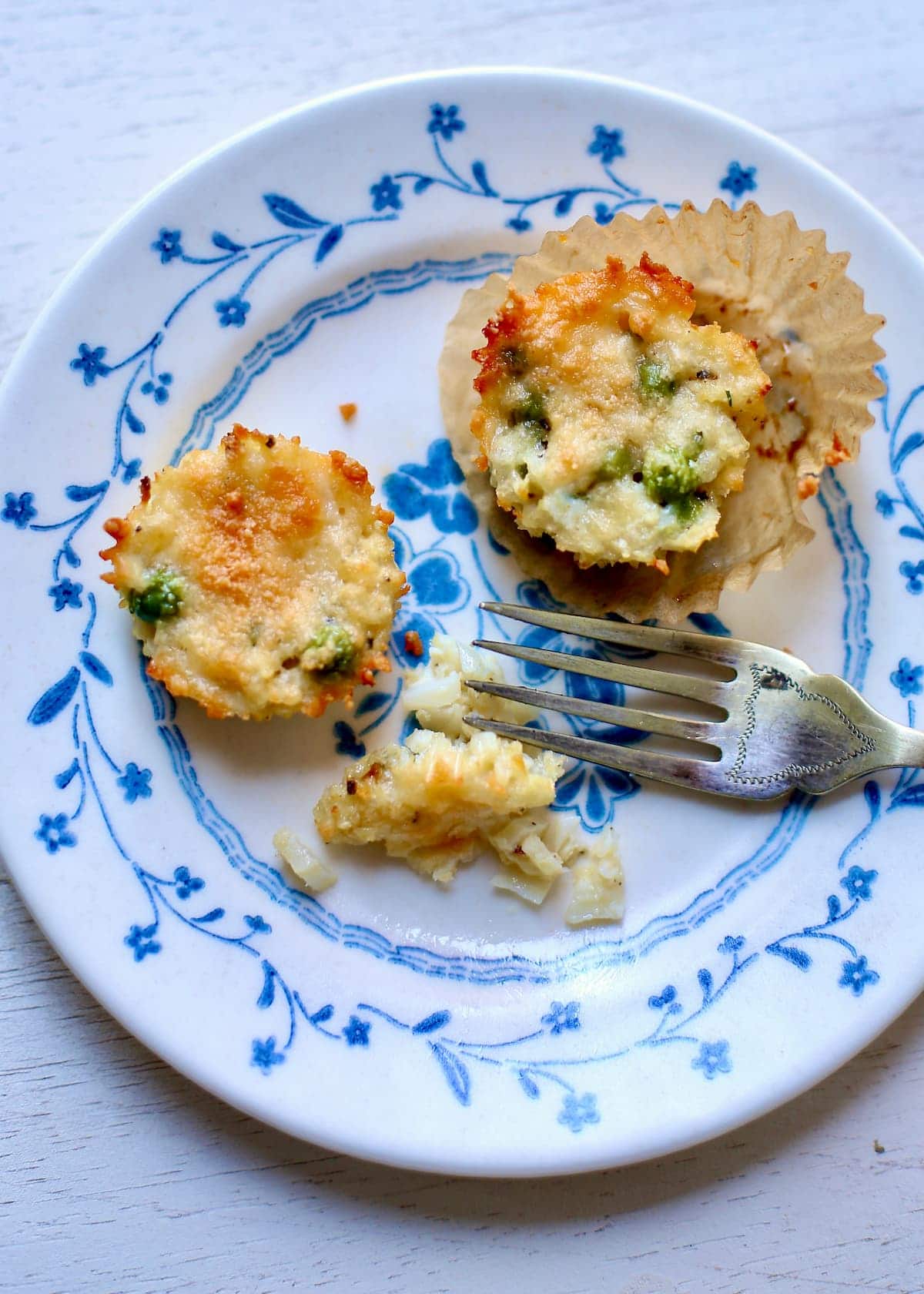 a blue flowered plate with two cauliflower bites and a fork on them.
