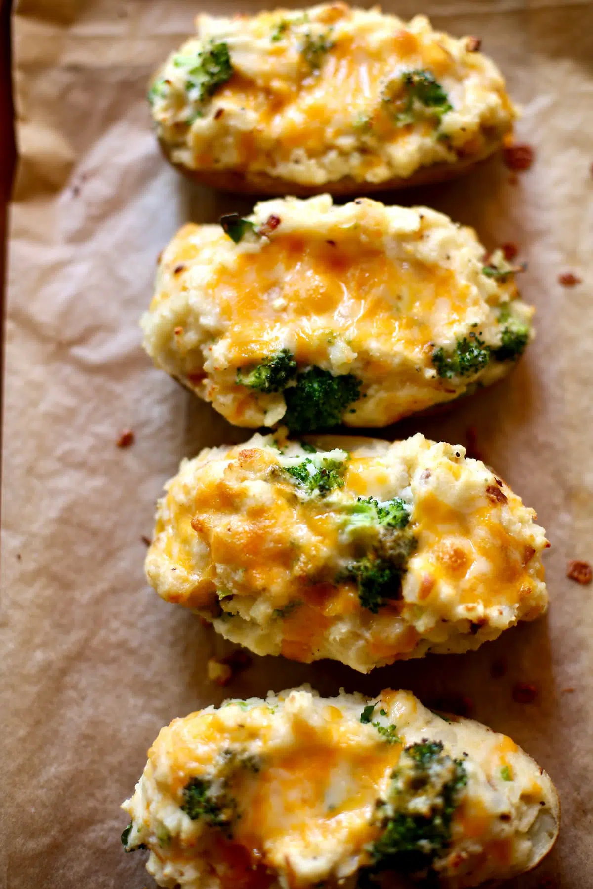 four potatoes with cheddar on a baking sheet.