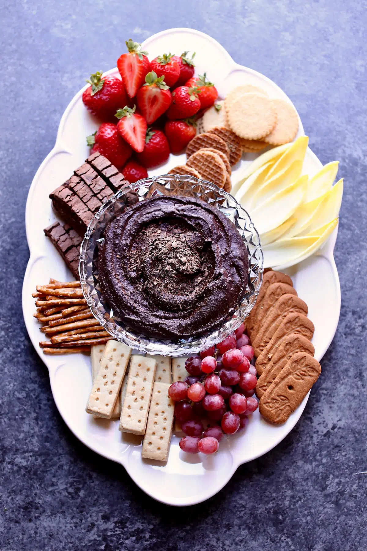 a dessert tray with a dark background, white serving platter.
