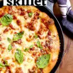 a skillet pizza with cheese and basil on a table with text overlay saying the recipe name.