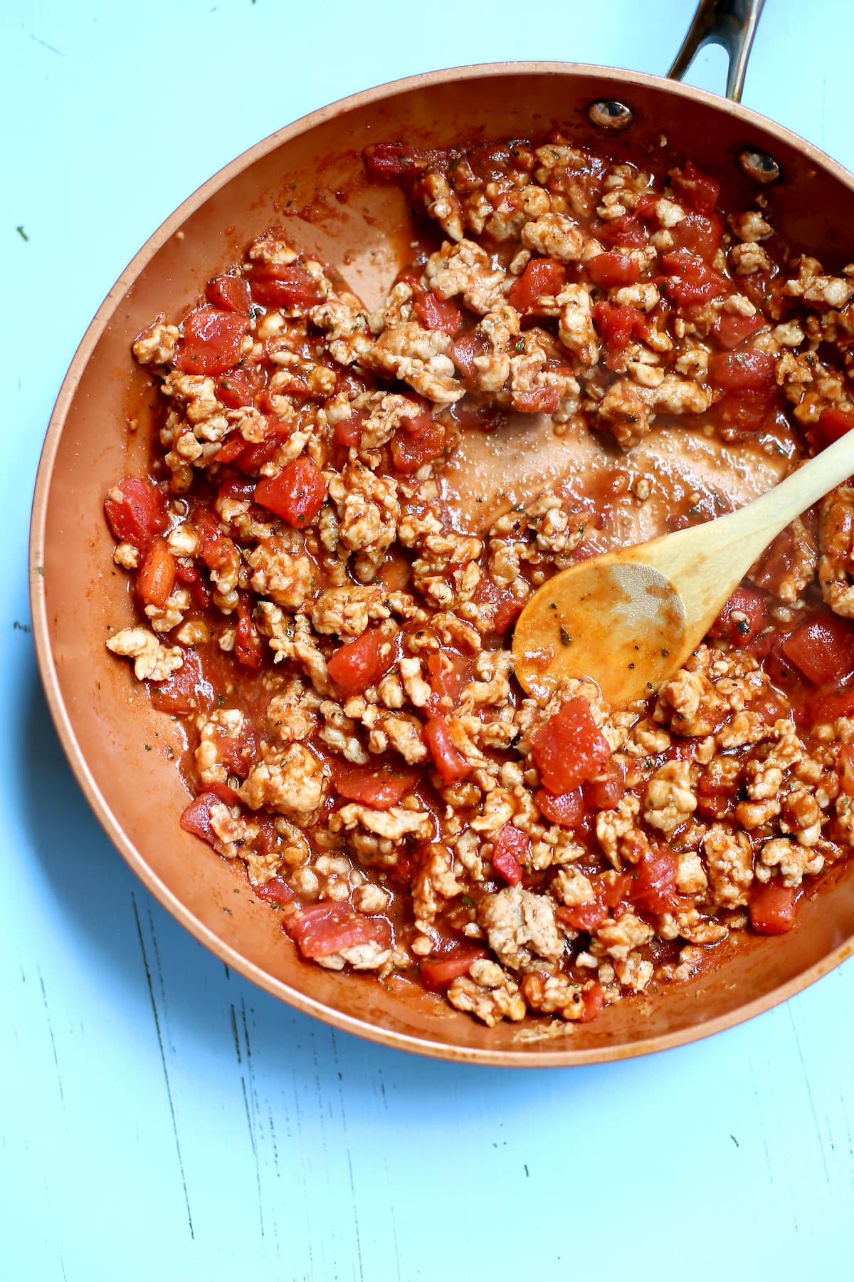 a skillet with ground turkey and sauce and tomatoes.