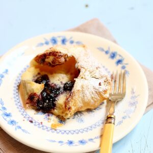 a cherry danish on a white plate with a fork.