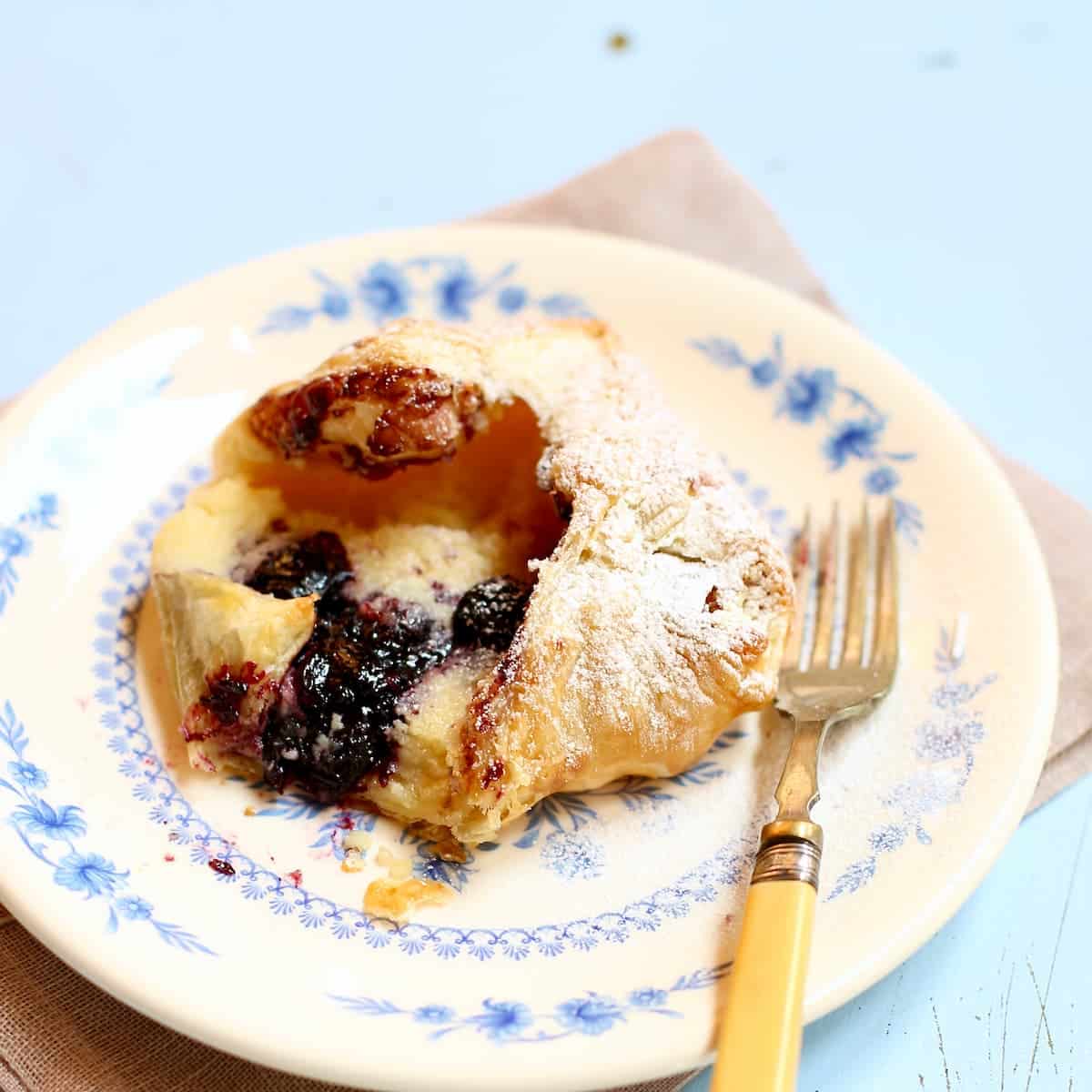 a cherry danish on a white plate with a fork.