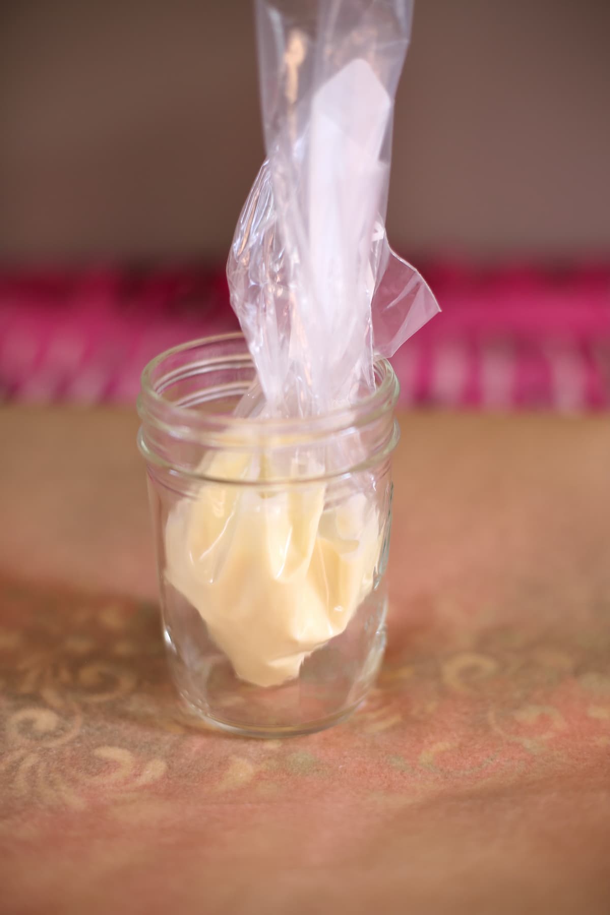 a jar of melted white chocolate on a plastic piping bag sitting on a table.