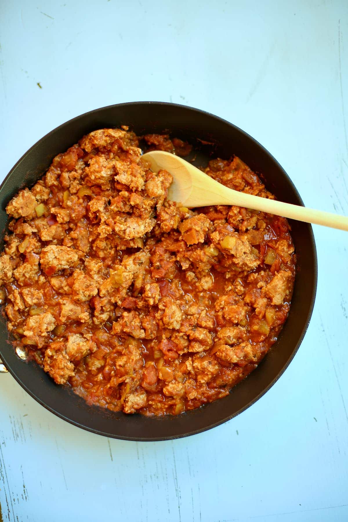 a skillet of taco meat that is cooked with a wooden spoon on the side.