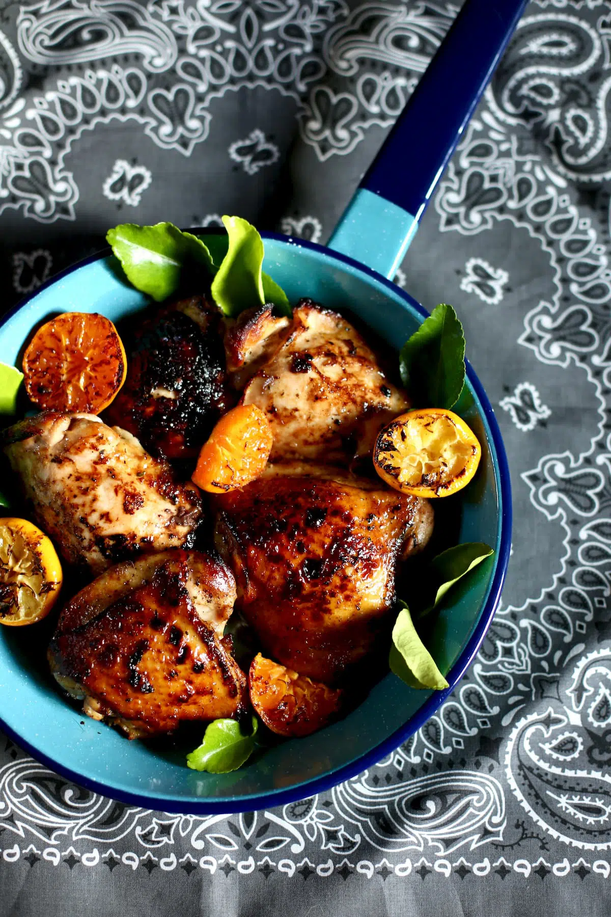 a skillet of chicken thighs with citrus segments on it.
