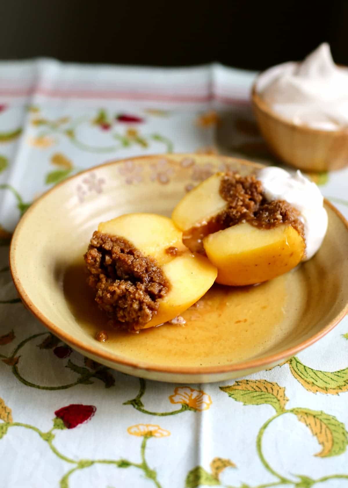 a baked apple cut in half to reveal the insides, on a yellow plate.