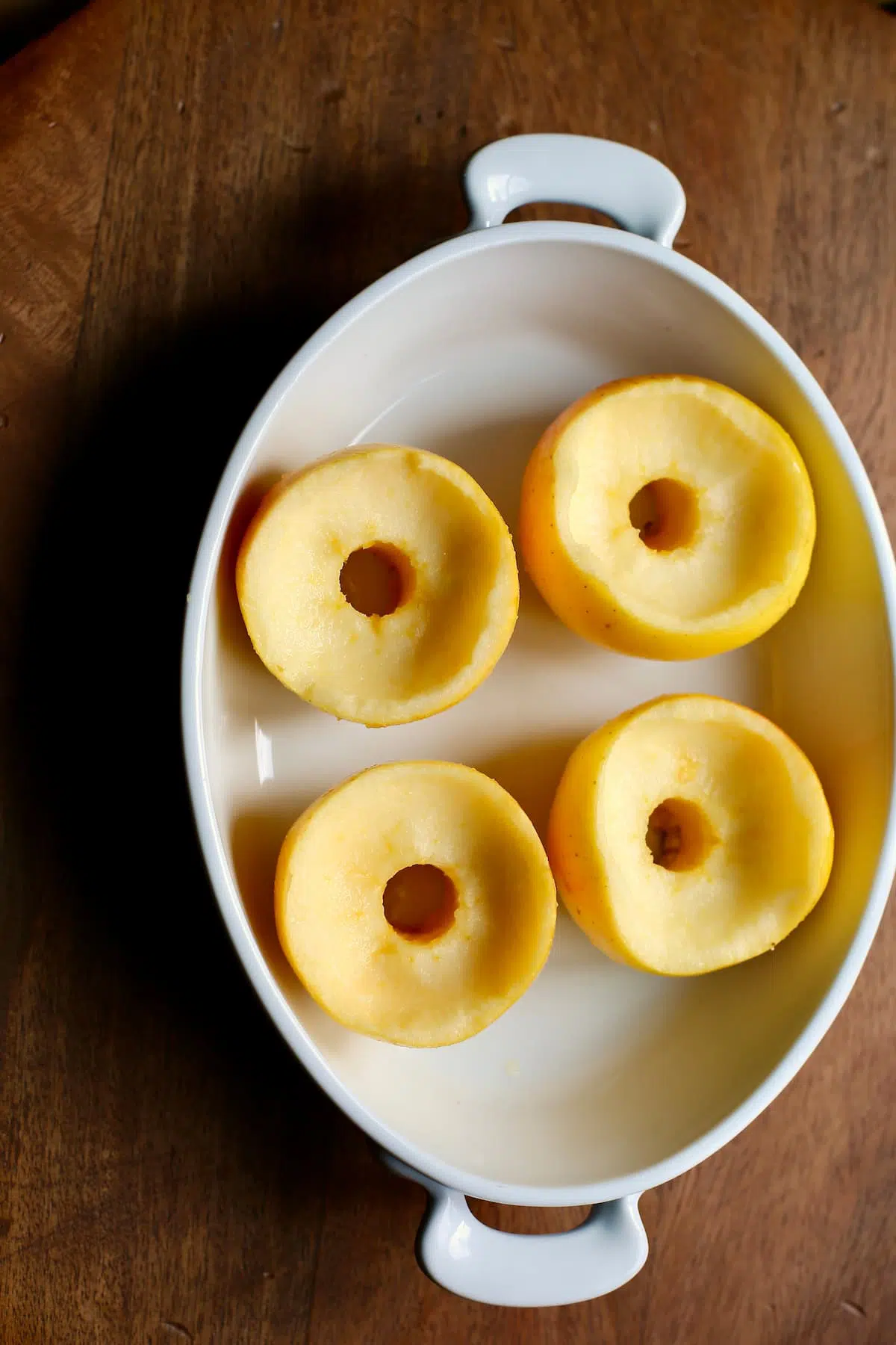 a baking dish with apples that have been cored and scooped out to make room for the filling of these baked apples.