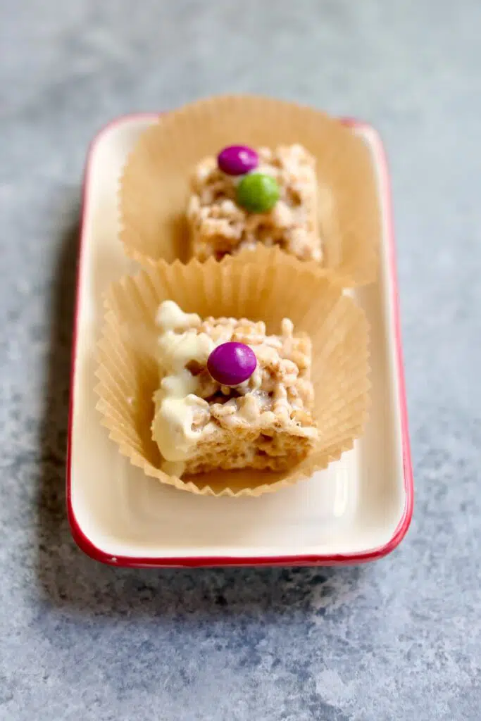 two cereal treats with a candy on top o a small white tray with pink rim.