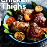 a blue skillet with chicken thighs in it and citrus fruit.