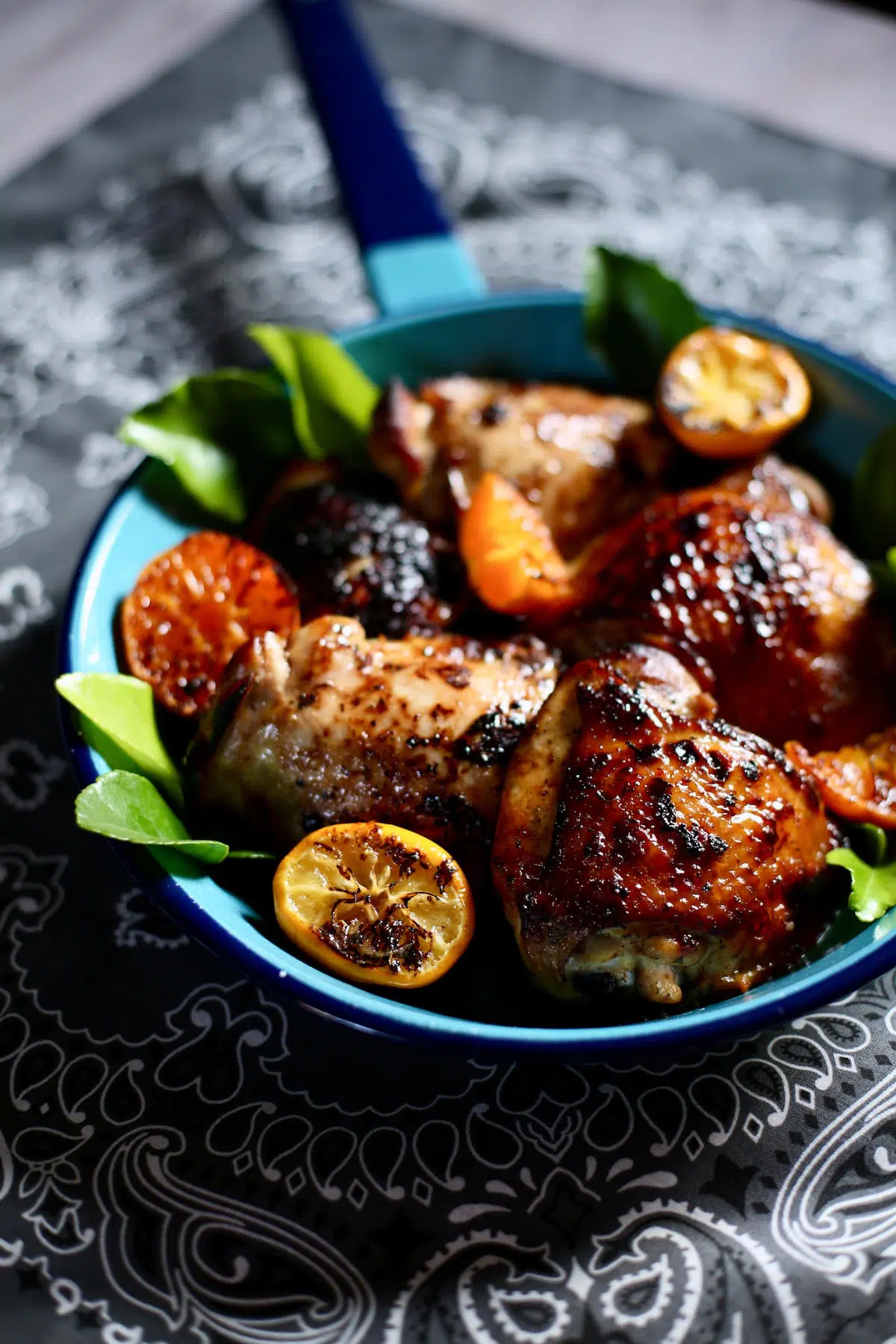a blue pan with chicken and oranges in it.