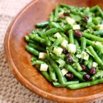 a bowl of green bean salad in a wooden bowl.