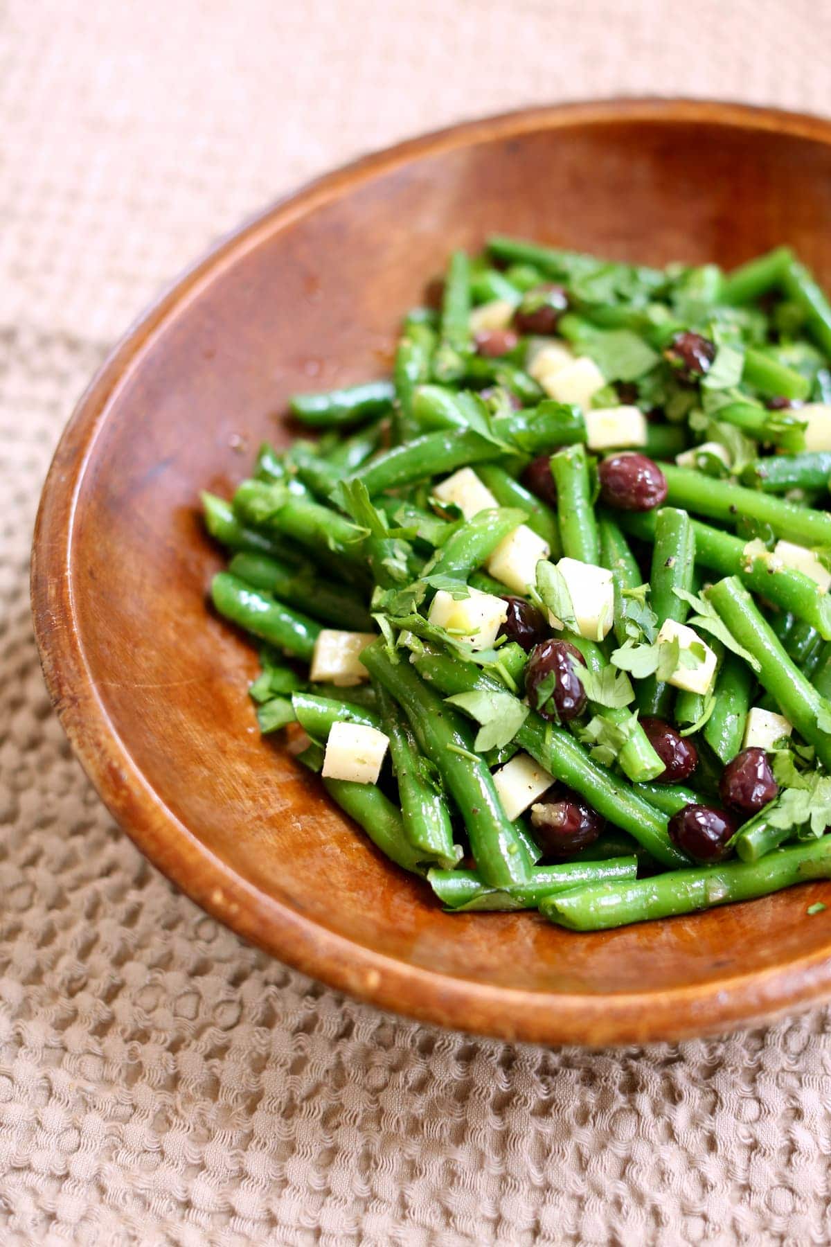 a bowl of green bean salad in a wooden bowl.