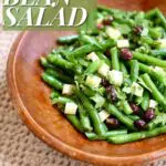 a wooden bowl with green bean salad in it and text overlay saying the recipe name.