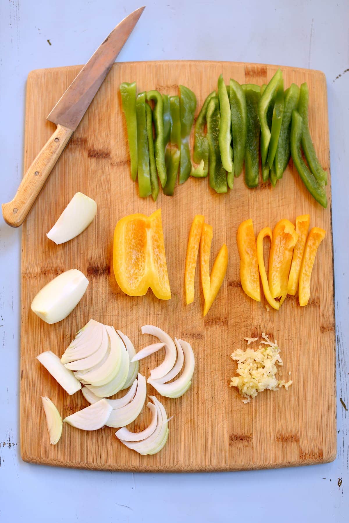 a cutting board with chopped vegetables on it and a knife.
