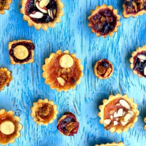 a photo of jam pies in various shapes and flavors on a blue table.
