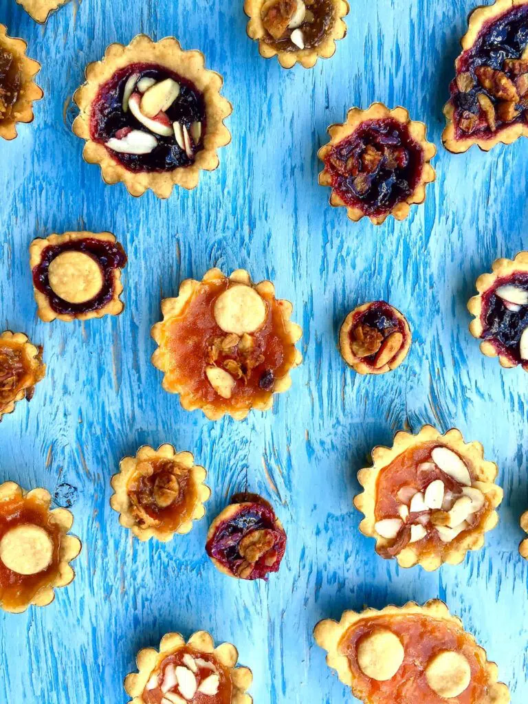 a dozen or so small jam pies on a blue table.