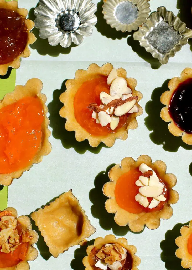 various sizes of mini pies on a table, filled wth jam.