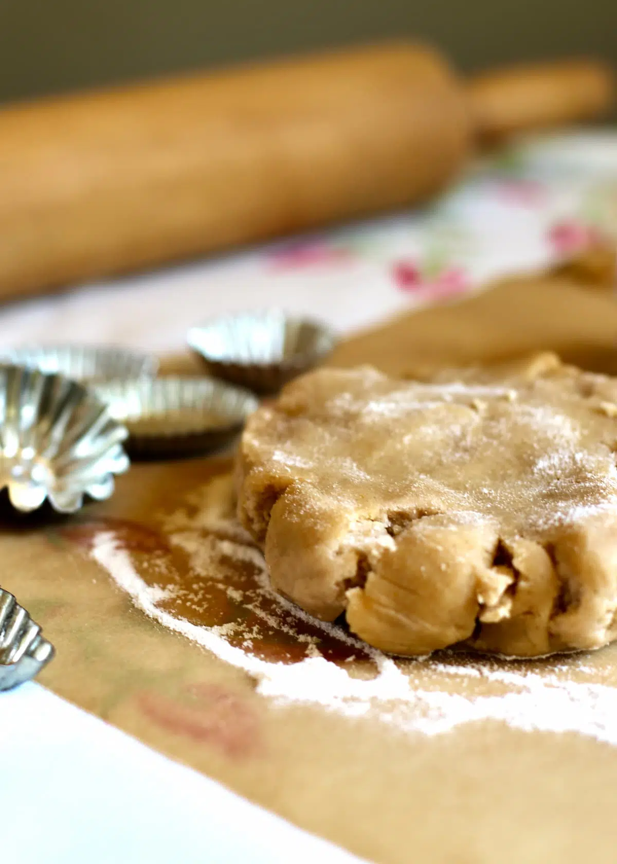 a round of pie dough and tart tins on a table.
