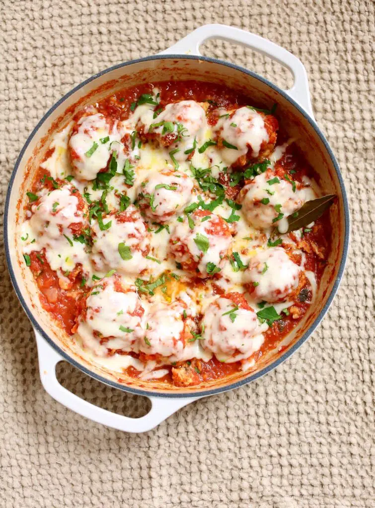 a skillet of cooked meatballs with cheese.