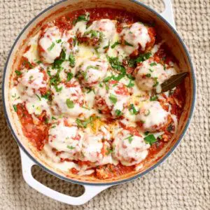 a skillet of meatballs with melted cheese.