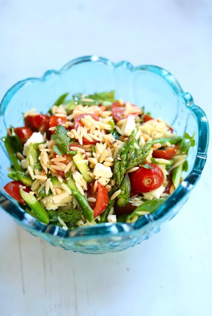 a blue bowl with a salad in it on a blue table.