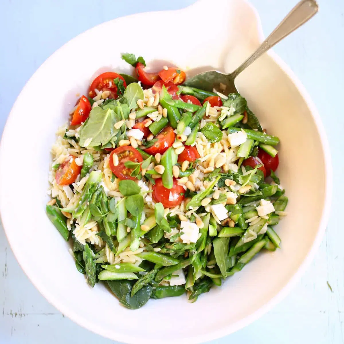 a white bowl with orzo salad inside of it.