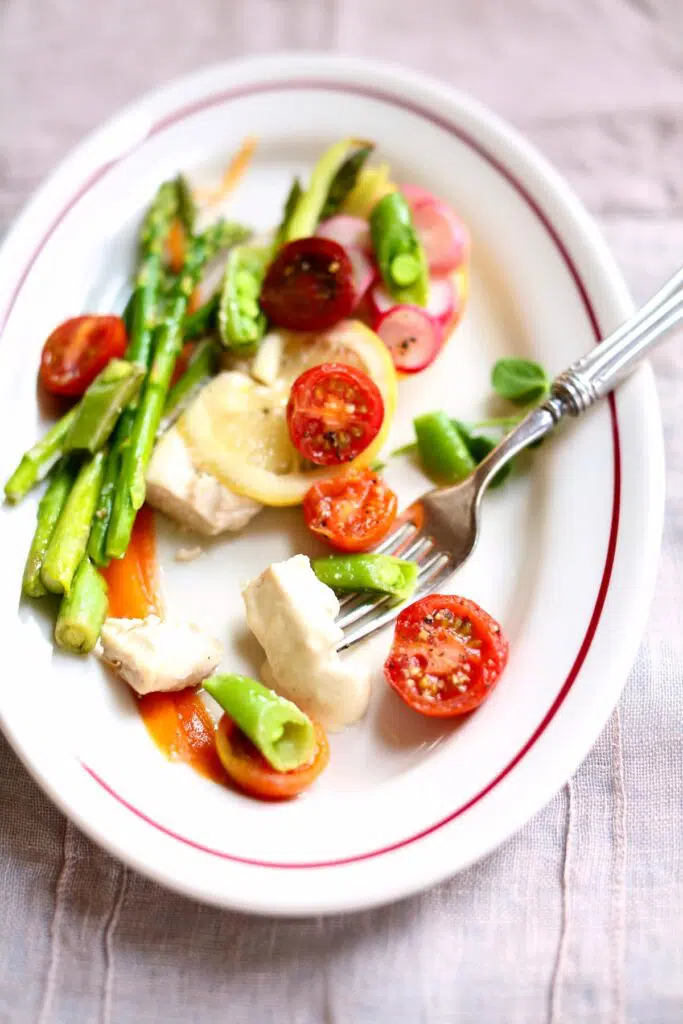 a white plate with chicken and vegetables on it.