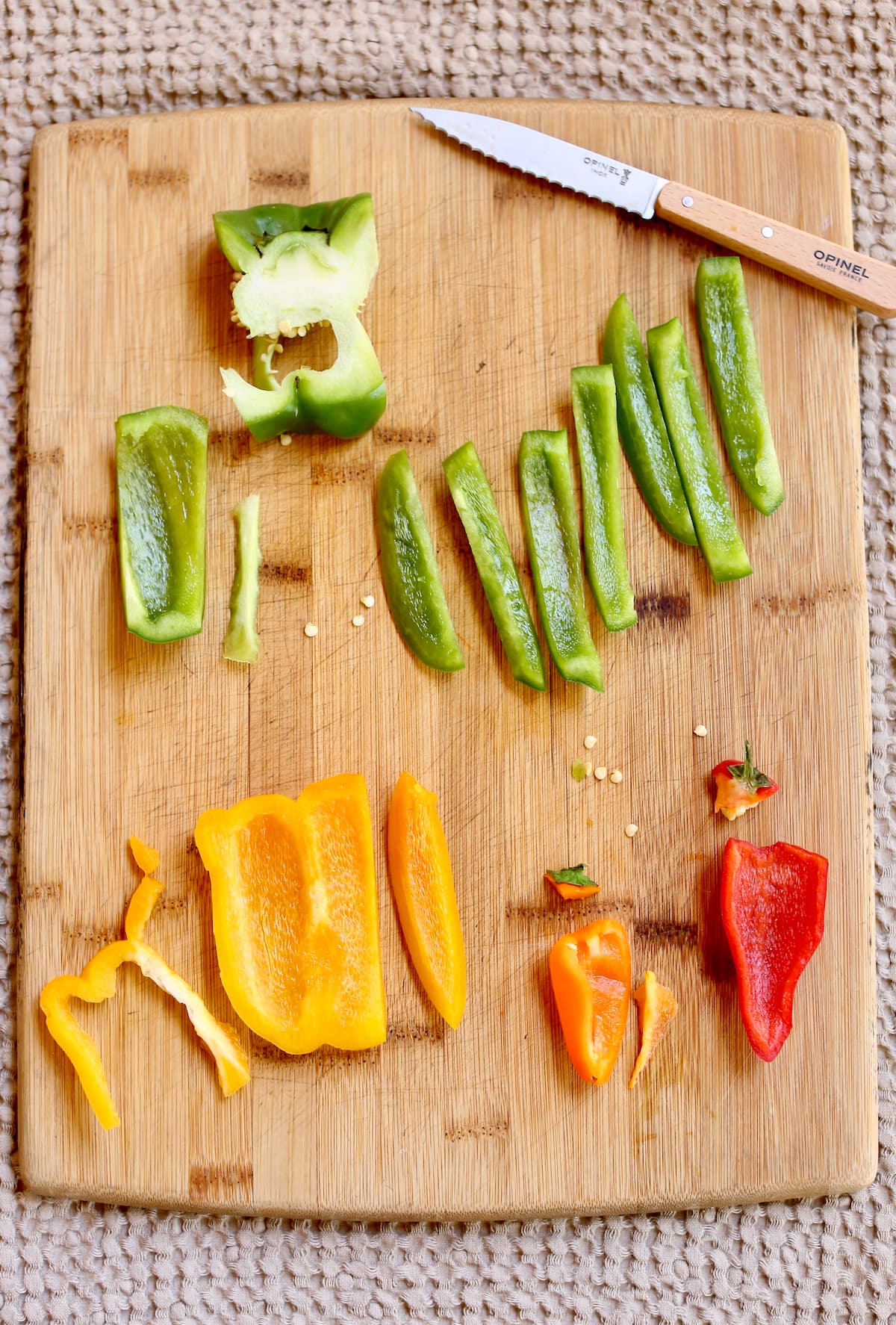a cutting board with various vegetables being cut with a paring knife.
