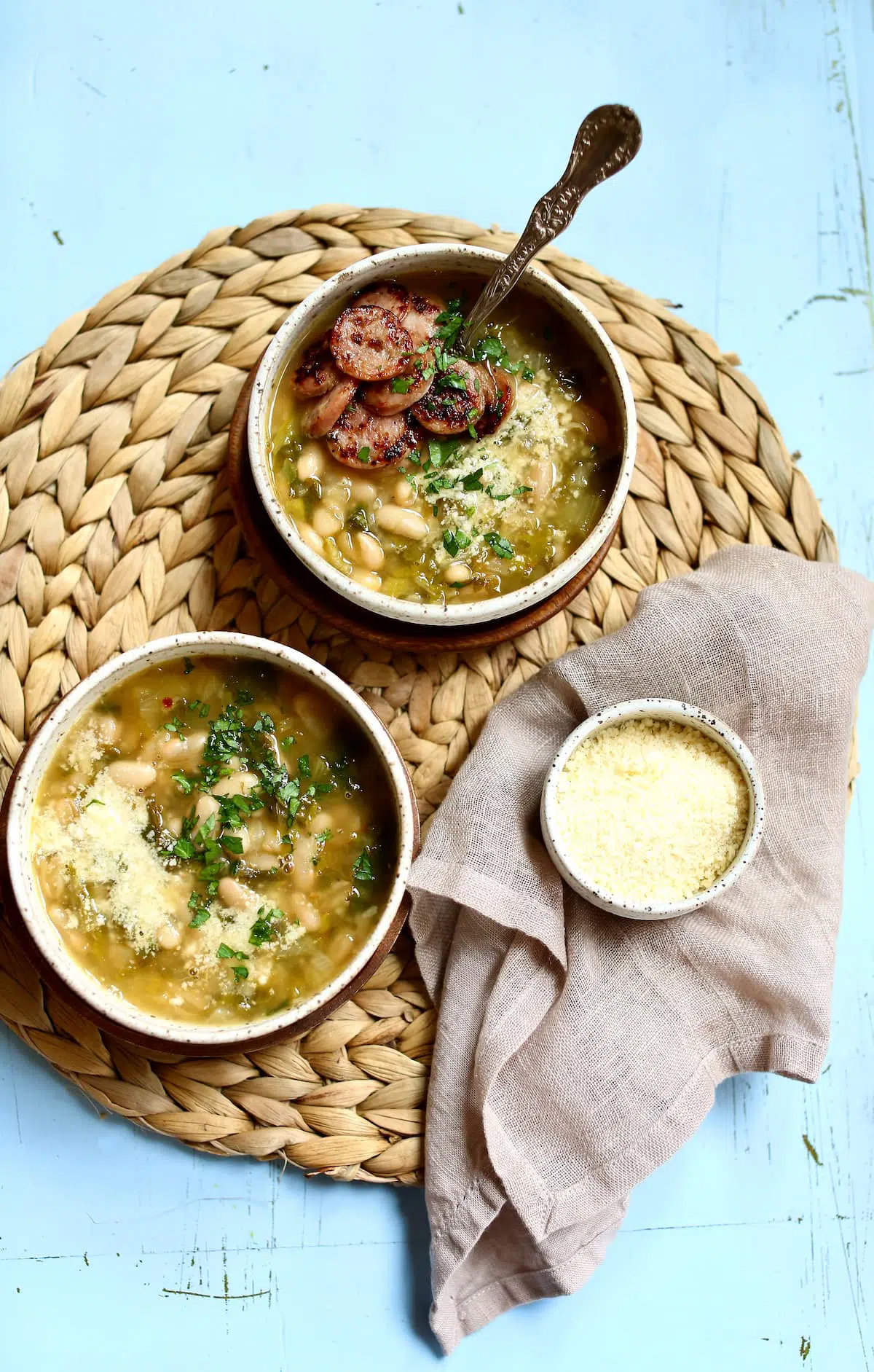 two bowls of soup with cheese next to it.