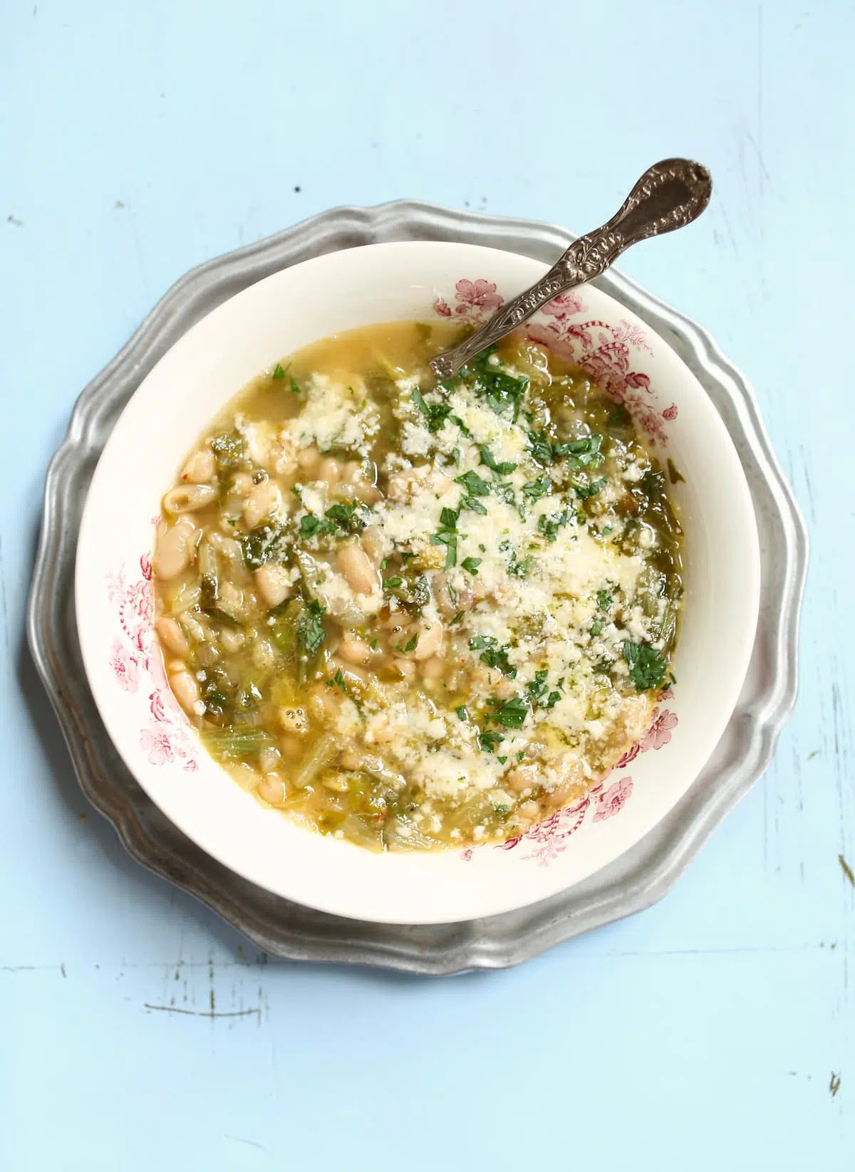 a large bowl of soup of white beans, greens and cheese.