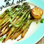 a close up photo of asparagus and grilled lemon on a platter.