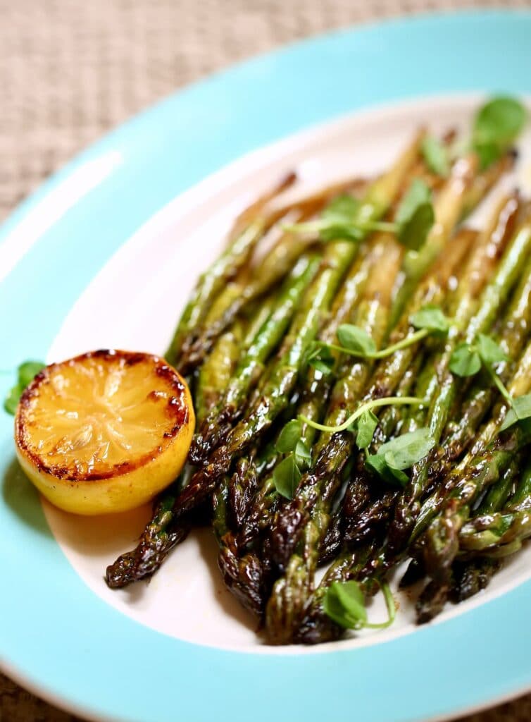 a platter of grilled asparagus with lemon.