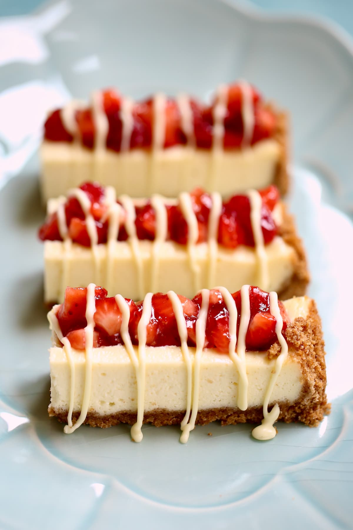 a plate of cheesecake bars with strawberry.